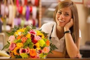 Beautiful smiling florist in her store with colorful bouquet